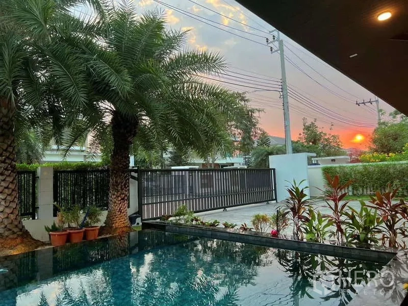 Detached House for rent or sale in Bang Phli, Samut Prakan - Pool terrace at sunset with palm trees and front gate view.