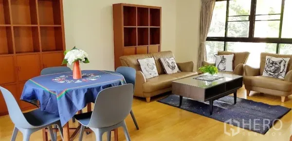 Detached House for rent in Chatuchak, Bangkok - Sunlit living and dining area with large windows, wood flooring, and built-in shelving.
