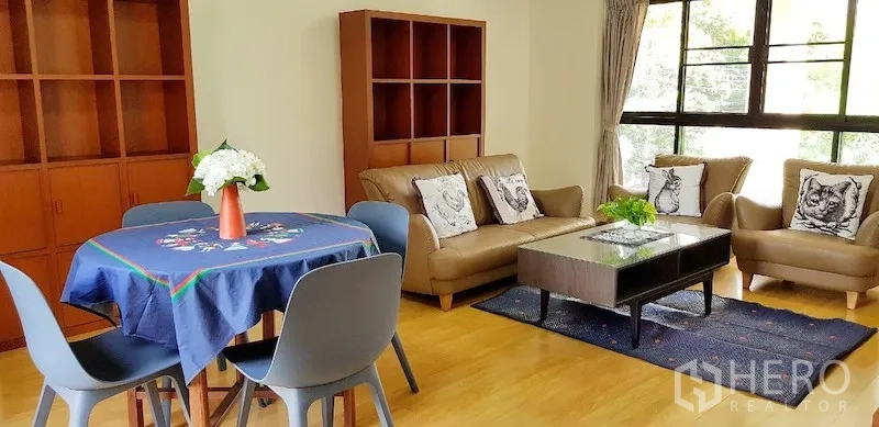 Detached House for rent in Chatuchak, Bangkok - Sunlit living and dining area with large windows, wood flooring, and built-in shelving.