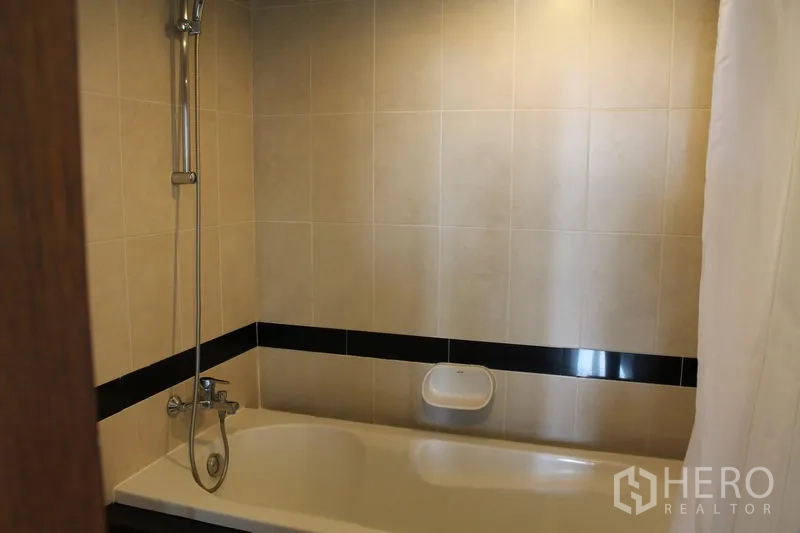 Apartment for rent in Bang Rak, Bangkok - Tiled bathroom featuring a bathtub with handheld shower.