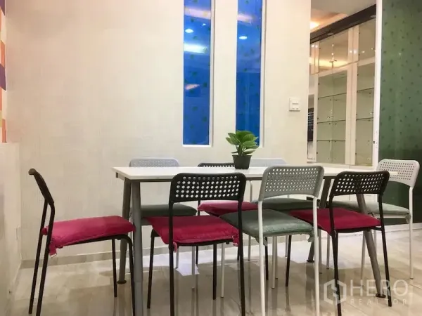 联排别墅 出租在Bang Rak, Bangkok - 用餐区，长桌配彩色餐椅，狭长窗与玻璃隔断。