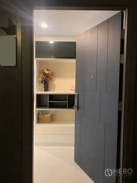 Condominium for rent in Watthana, Bangkok - Entrance door opening to a foyer with built-in white shelving and soft recessed lighting.