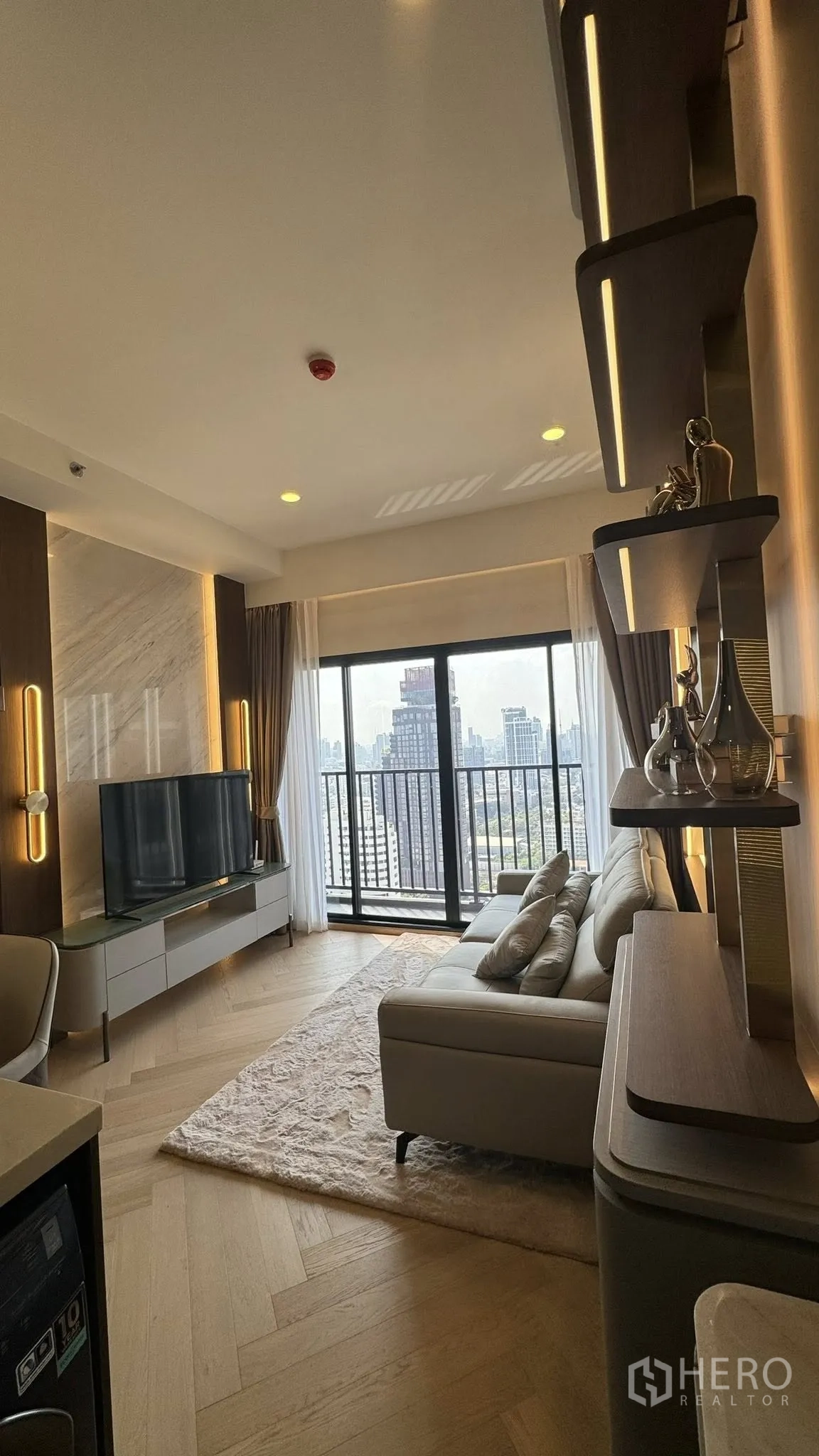 คอนโด for rent in Watthana, Bangkok - ห้องนั่งเล่นสว่างพร้อมโซฟา ชั้นวางทีวี ชั้นบิลท์อิน พื้นไม้ และระเบียงชมวิวสกายไลน์เมือง
