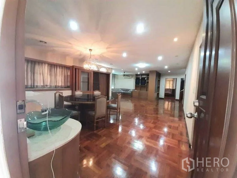 Detached House for rent in Watthana, Bangkok - Spacious open‑plan living and dining area with chandelier and polished wooden parquet floors.