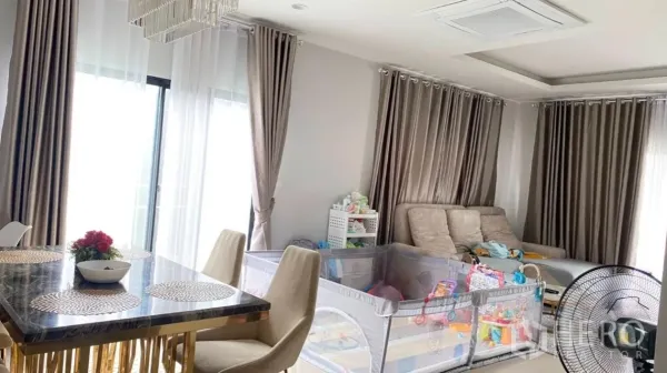 Detached House for rent or sale in Lam Luk Ka, Pathum Thani - Bright dining and lounge area with marble table, chandelier, large curtains, and a family playpen.