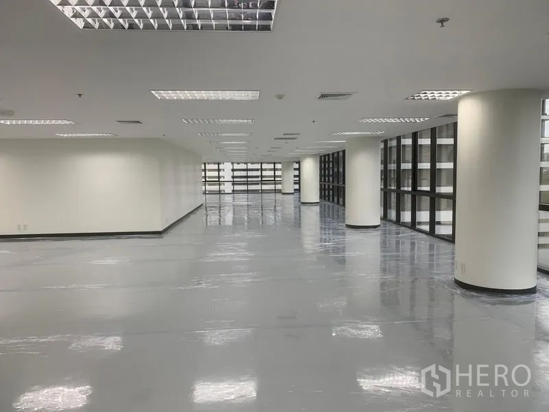 Office Space for rent in Bang Rak, Bangkok - Spacious office floor with round columns, reflective flooring, and grid ceiling lighting.
