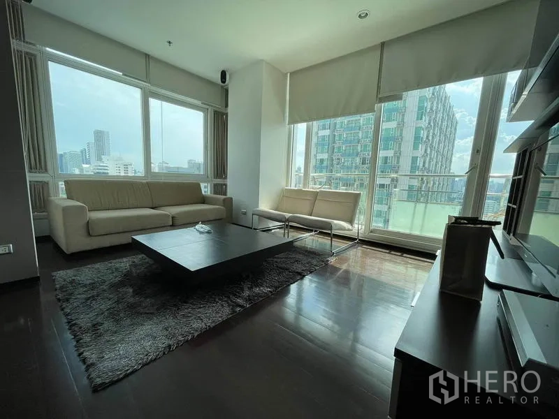 公寓 出租或出售在Watthana, Bangkok - 采光充足的客厅，落地窗与城市景观，米色沙发与深色木地板
