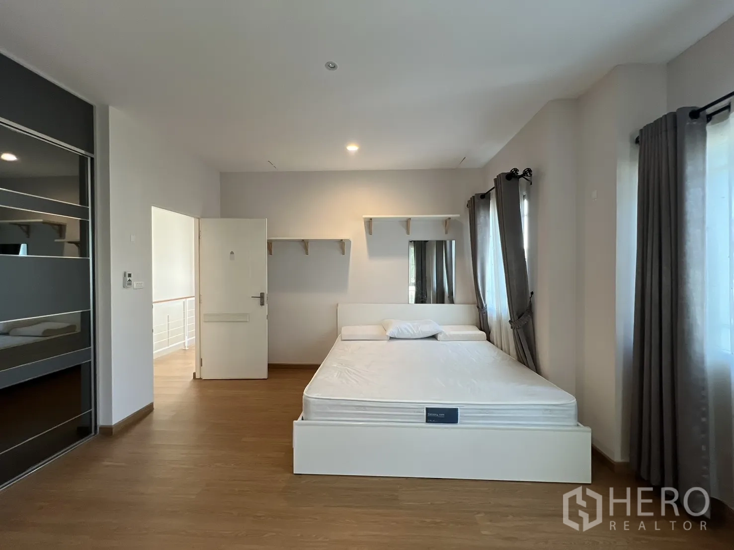 Detached House for rent in Bang Kapi, Bangkok - Bedroom with a bedframe, shelves, and multiple windows with curtains.