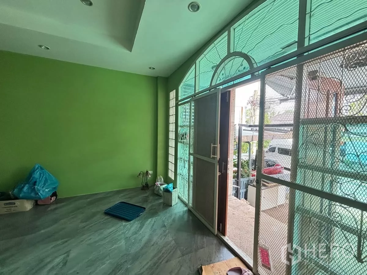 Shophouse for rent in Watthana, Bangkok - Front room with arched glass panels and metal security gate opening to the street.