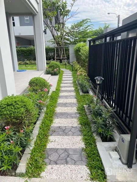 独立式住宅 出售在Bang Kapi, Bangkok - 前庭步道，踏石与碎石铺就，两侧修剪灌木和黑色栅栏。