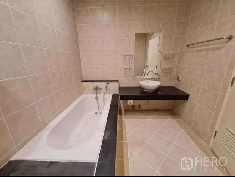 Townhouse for rent in Phra Khanong, Bangkok - Bathroom featuring a built-in bathtub, vessel sink vanity and neutral tiles.