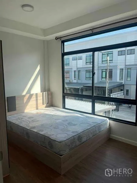 Townhouse for rent in Suan Luang, Bangkok - Bedroom with queen bed and wide window overlooking the townhouse street.