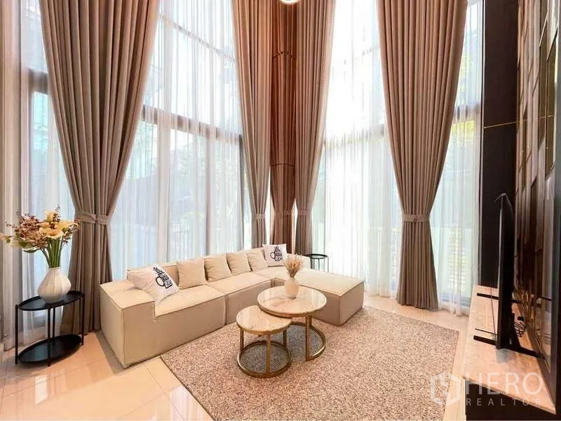独立式住宅 出租在Bang Sue, Bangkok - 挑高双层客厅，落地窗帘与转角沙发