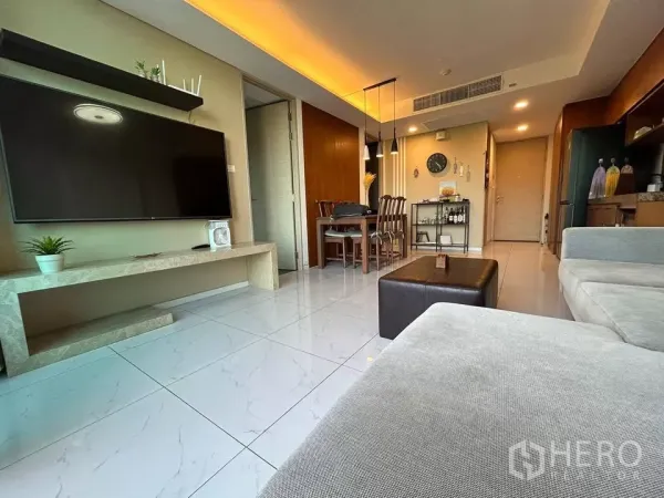 公寓 出租在Watthana, Bangkok - 客厅朝入口视角，墙挂大电视与吊灯餐区
