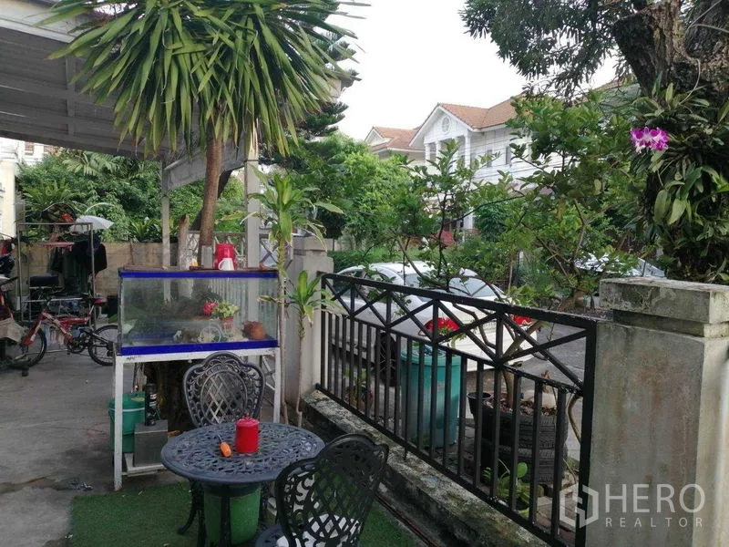 独立式住宅 出售在Prawet, Bangkok - 前院露台，户外桌椅、绿植与金属围栏。