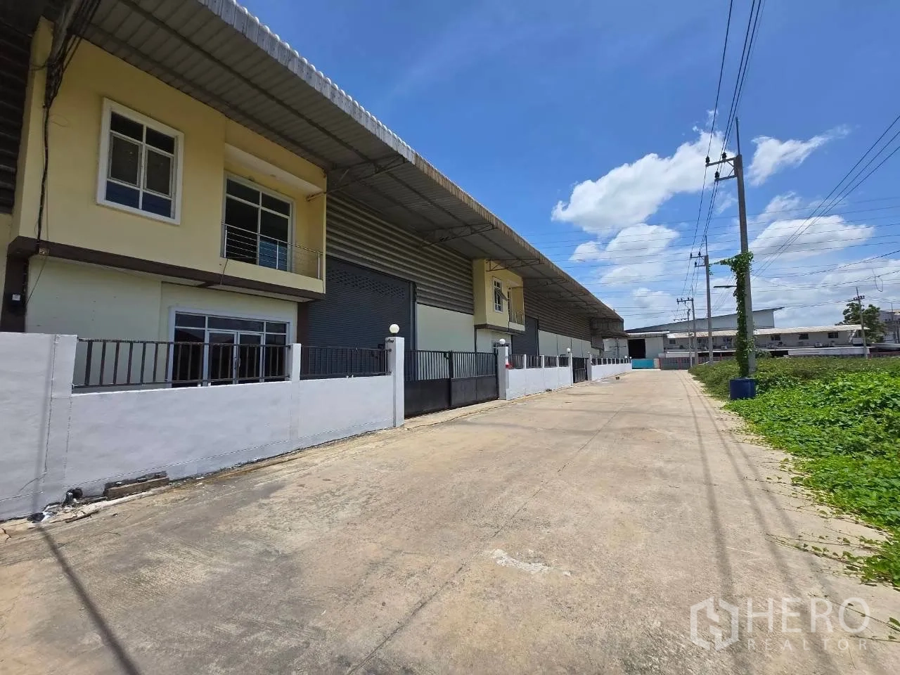 仓库 for rent or sale in Mueang Samut Sakhon, Samut Sakhon - 仓库外立面带办公室区、大卷闸门以及宽阔的进出道路。
