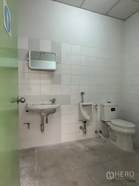 Factory for rent in Khlong Luang, Pathum Thani - Clean tiled restroom with sink, urinal and toilet inside the factory building.