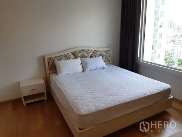 Condominium for rent in Khlong Toei, Bangkok - Sunny bedroom with queen bed, bedside table and large window with city view