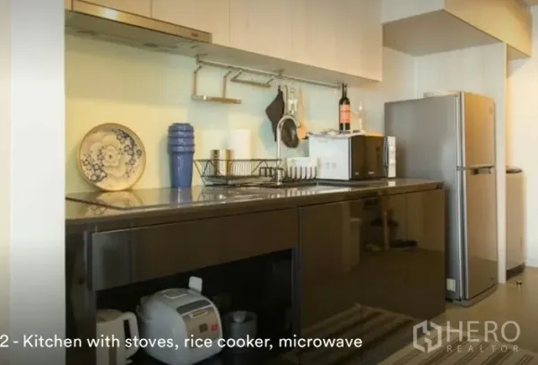 Condominium for rent in Phaya Thai, Bangkok - Modern kitchen in a Phaya Thai condominium near BTS Ari with glossy cabinets, hob, microwave, rice cooker and fridge.