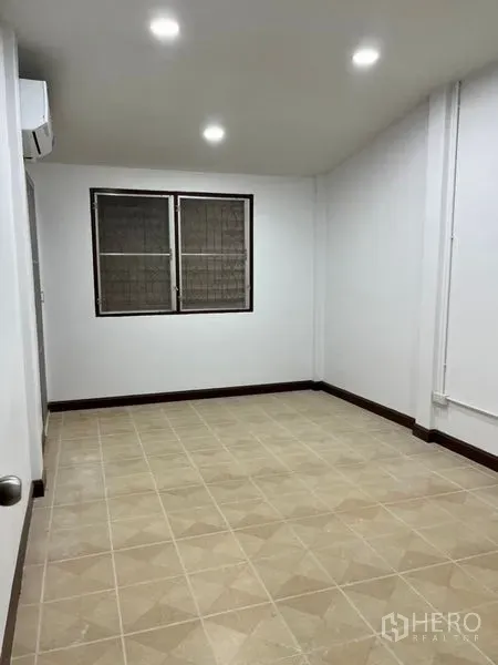 Townhouse for rent in Din Daeng, Bangkok - Secondary bedroom with neutral floor tiles, two windows, and ceiling spotlights.