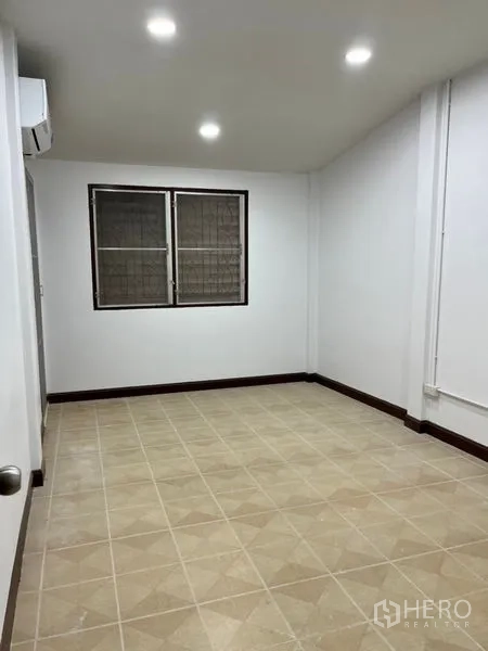 Townhouse for rent in Din Daeng, Bangkok - Secondary bedroom with neutral floor tiles, two windows, and ceiling spotlights.