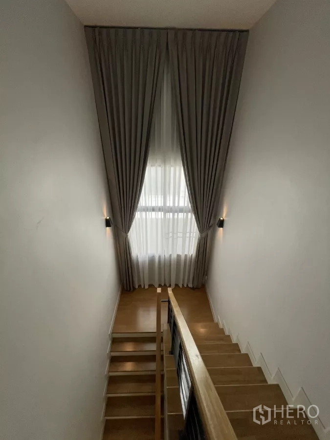 独立式住宅 出租在Bang Phli, Samut Prakan - 楼梯间高窗与全高窗帘，木质台阶与扶手。