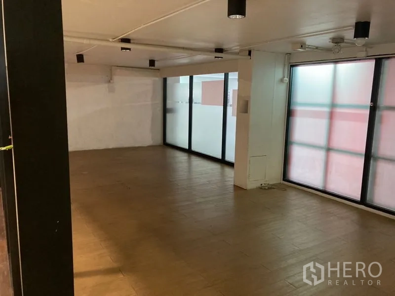 Retail Space for rent in Khlong Toei, Bangkok - Open-plan shop interior with wood-look tile flooring, frosted windows, and ceiling spotlights.