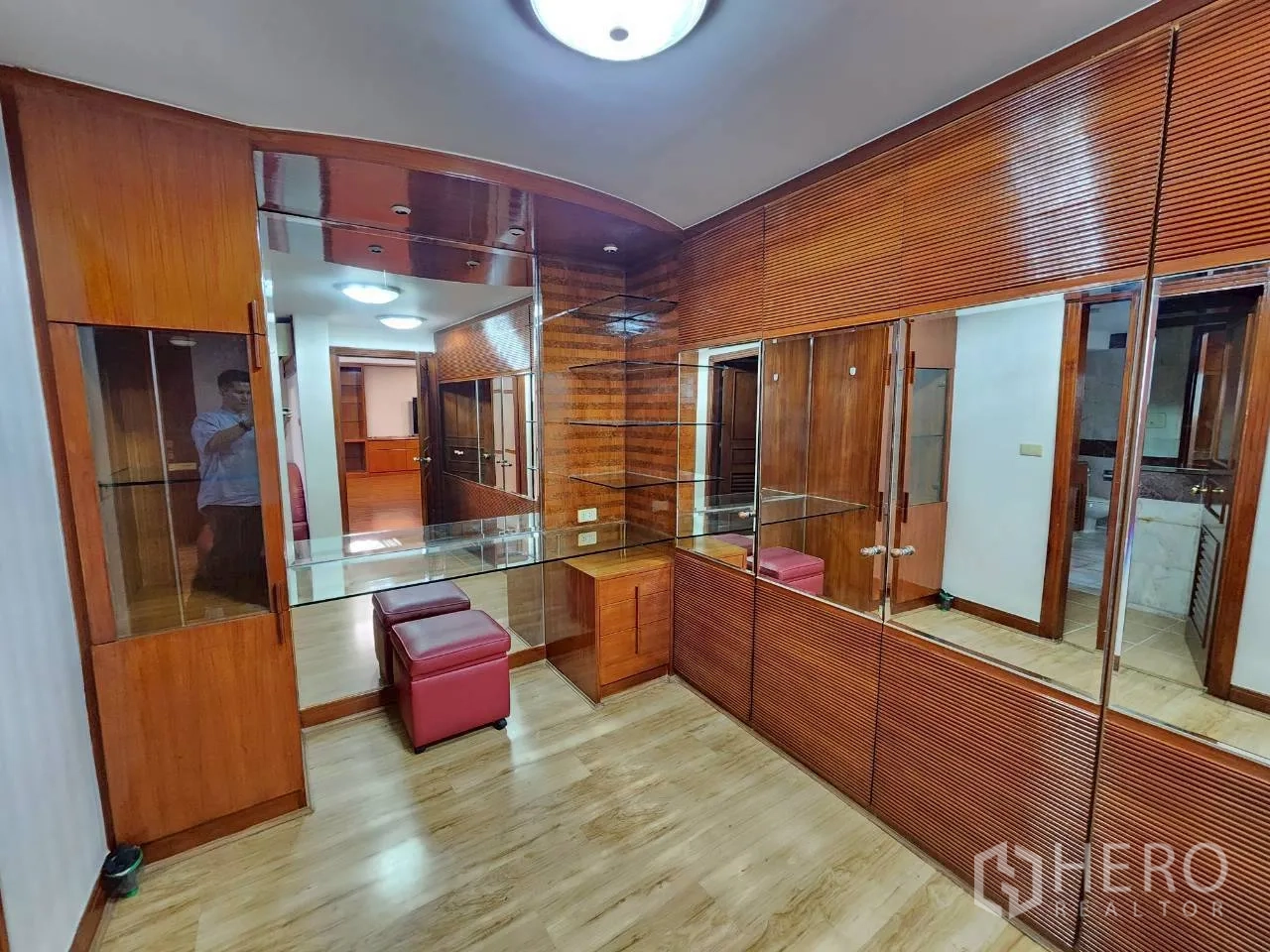 Condominium for rent in Khlong Toei, Bangkok - Dressing room with wall-to-wall mirrors, glass shelves and wood cabinetry.