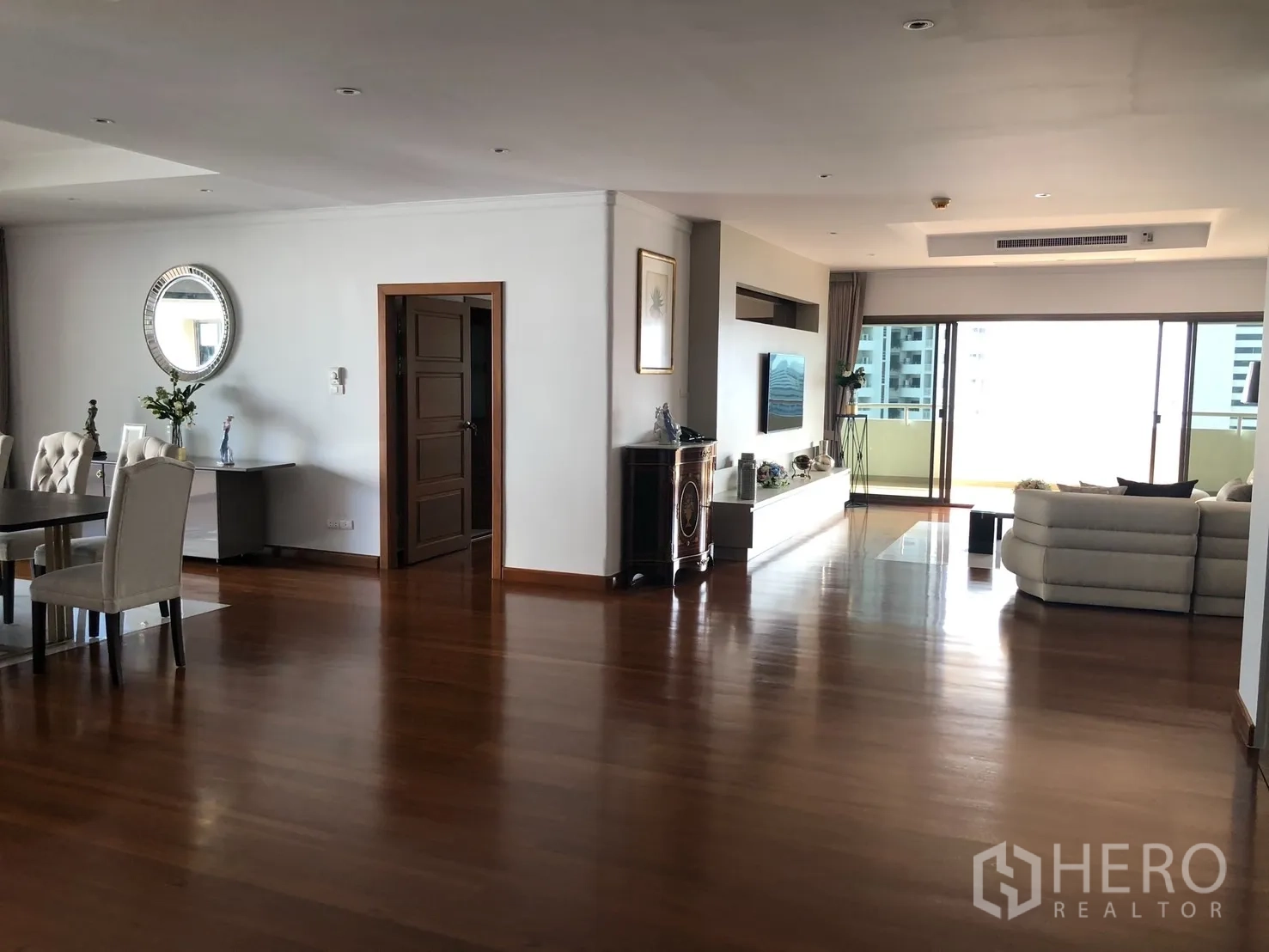 Condominium for rent in Bangkok - Open-plan living and dining area with wide hardwood floors and balcony doors.