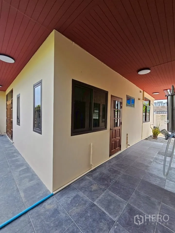 带办公室的家 for rent in Wang Thonglang, Bangkok - 侧边有顶走廊，红色天花、灰色地砖，窗户与木门成排。