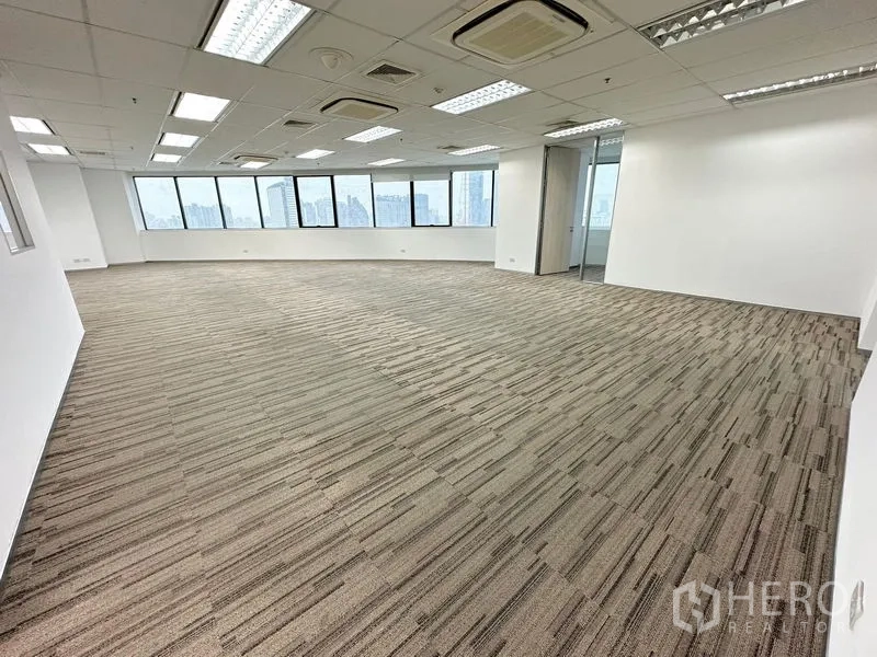 办公空间 出租在Watthana, Bangkok - 明亮的开放式办公室，地毯地面、吊顶灯具，整面窗户可观赏曼谷天际线。