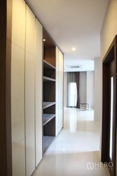 บ้าน ให้เช่าในBang Na, Bangkok - โถงทางเดินกว้างพร้อมชั้นวางของแบบบิลท์อินและพื้นเงาเชื่อมสู่พื้นที่นั่งเล่น