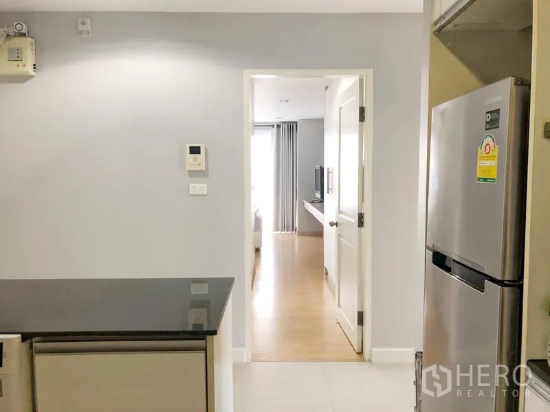 Condominium for rent or sale in Khlong Toei, Bangkok - Kitchen corridor with stainless fridge and view toward the bedroom door.