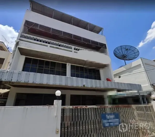 带办公室的家 出租在Suan Luang, Bangkok - 多层住宅式办公楼外观，带前院围栏、大片玻璃窗与金属雨棚，蓝天下的建筑。
