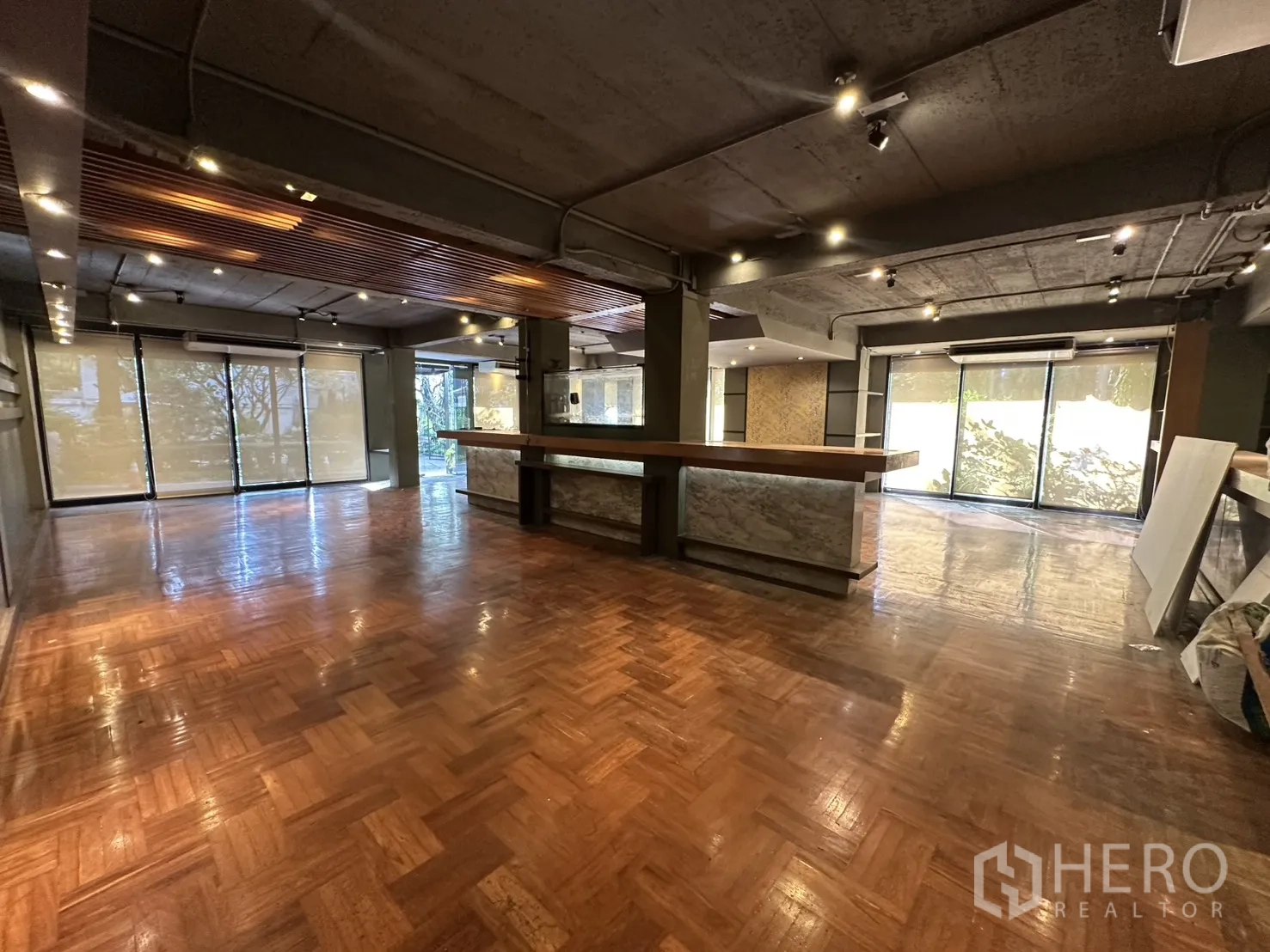 Retail Space for rent in Watthana, Bangkok - Open space with wood‑slat ceiling feature, polished parquet, and full‑height glazing to greenery.