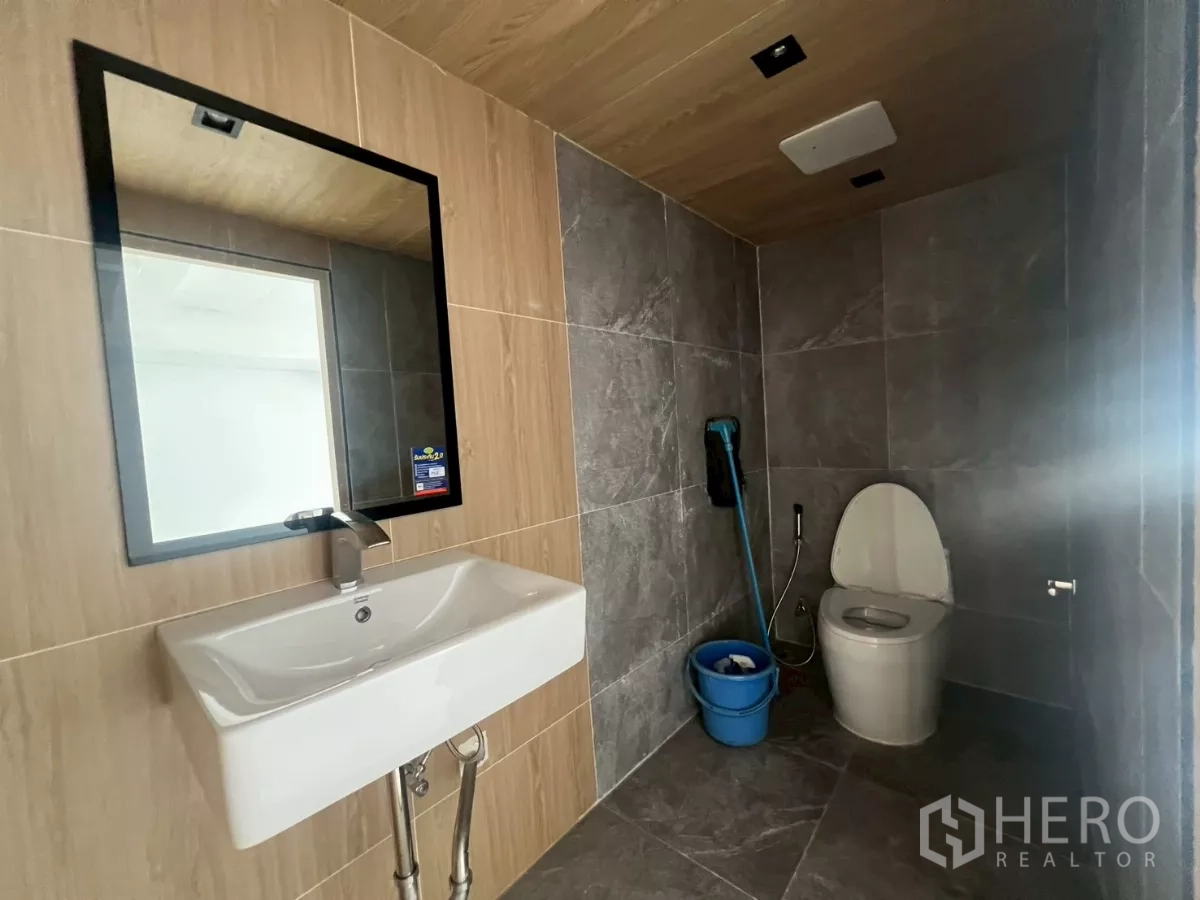 Retail Space for rent in Pathum Wan, Bangkok - Modern restroom with tiled walls, mirror, basin, and toilet.