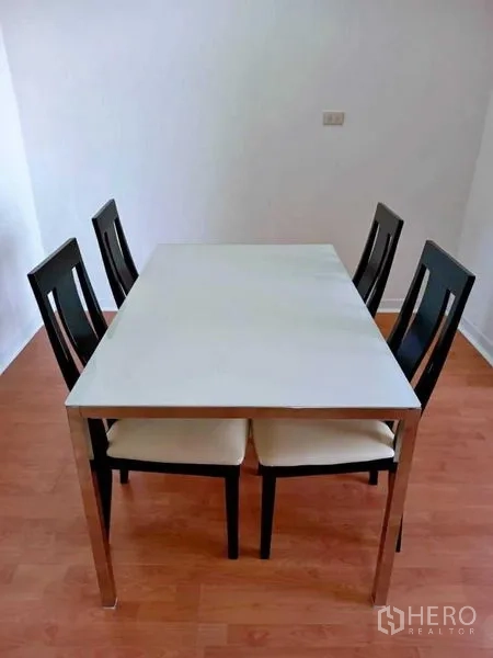 Condominium for rent in Khlong Toei, Bangkok - Four-seat dining table with black chairs on wood laminate flooring.