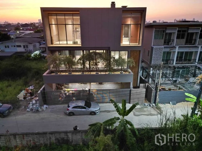 独立式住宅 出售在Lat Phrao, Bangkok - 三层现代住宅后立面，落地窗与夕阳景致。