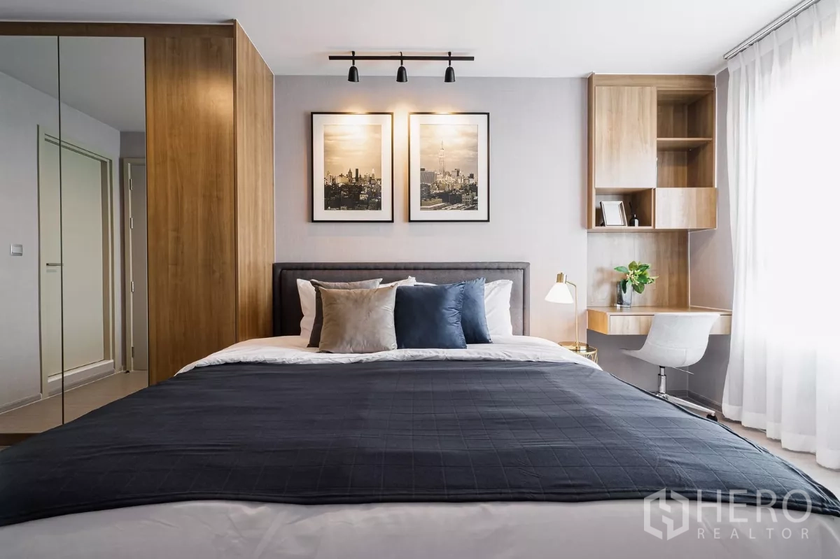 Condominium for rent in Chatuchak, Bangkok - Master bedroom with built-in wardrobe, study nook and warm lighting.