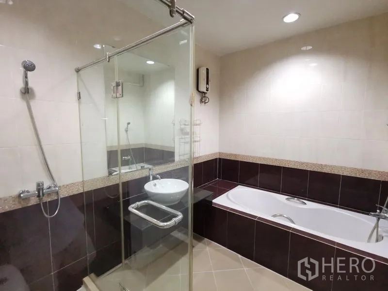 Townhouse for rent in Yan Nawa, Bangkok - Modern bathroom with glass-enclosed shower, separate bathtub, and tiled walls under recessed lighting.