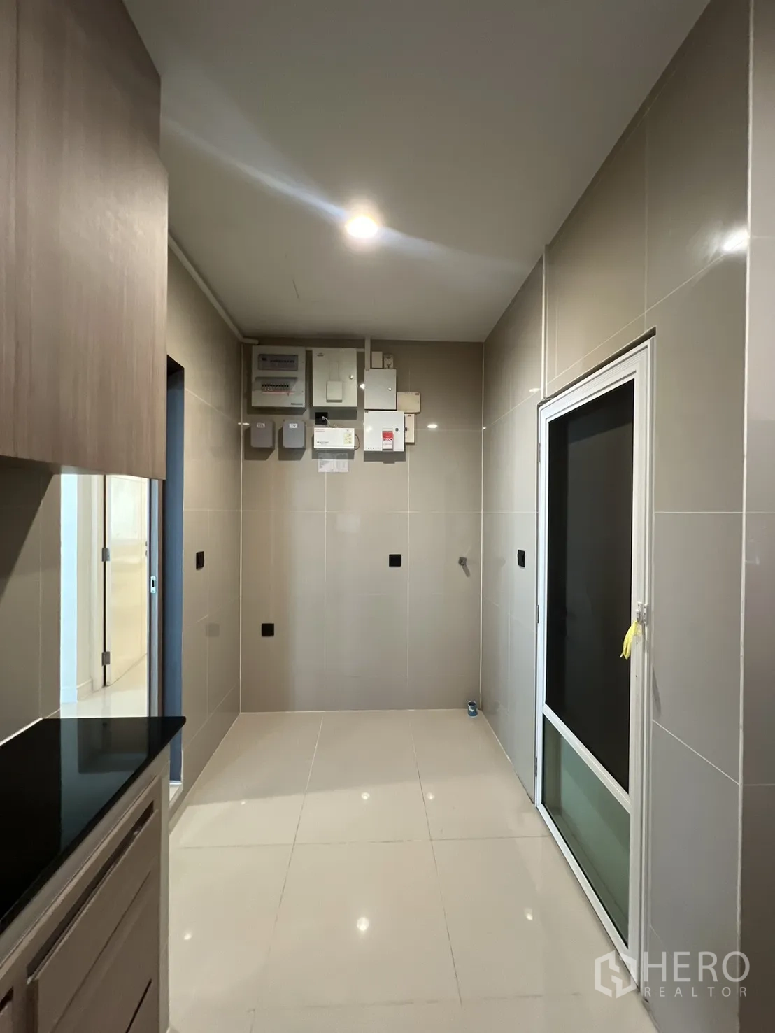 Detached House for sale in Bang Kapi, Bangkok - Utility area off the kitchen with tiled walls and exterior door.