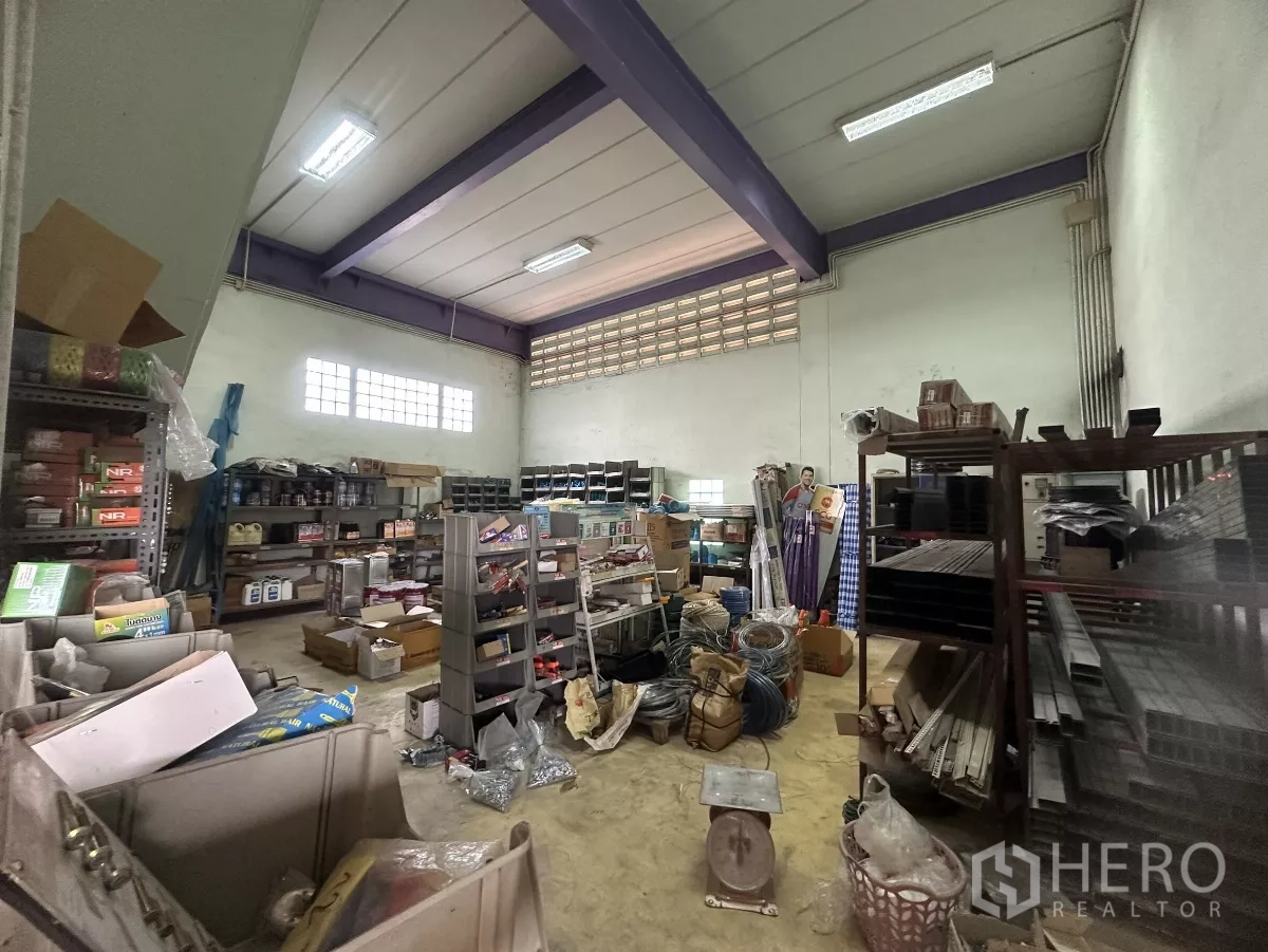 Warehouse for rent in Mueang Nonthaburi, Nonthaburi - Secondary storage room with shelving, fluorescent lighting and assorted inventory.
