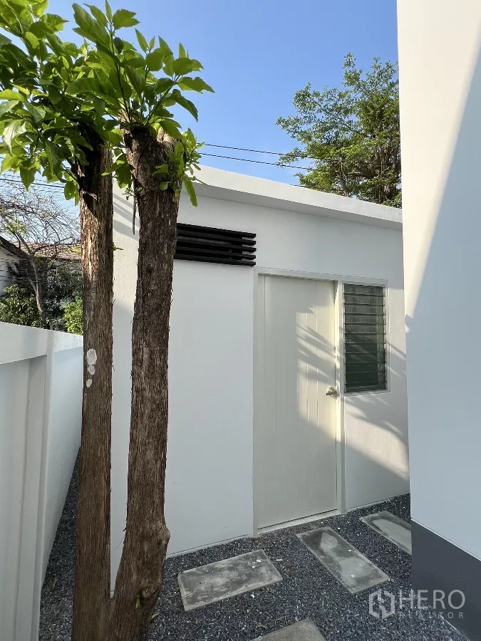 独立式住宅 出租或出售在Saphan Sung, Bangkok - 小型储物间，白门旁有小树。