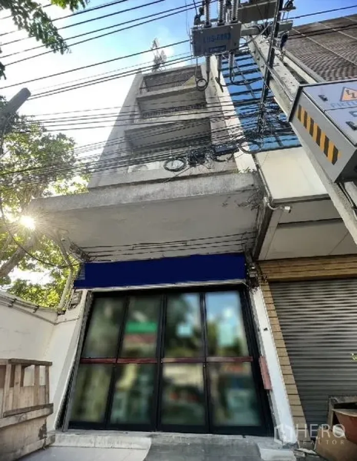 Shophouse for rent in Watthana, Bangkok - Multi-storey shophouse exterior with wide glass storefront and blue awning on a Sukhumvit side street near BTS Thong Lo in Watthana, Bangkok.
