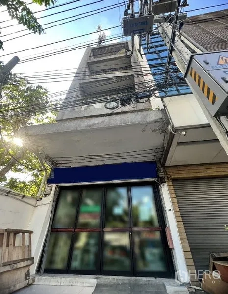 Shophouse for rent in Watthana, Bangkok - Multi-storey shophouse exterior with wide glass storefront and blue awning on a Sukhumvit side street near BTS Thong Lo in Watthana, Bangkok.