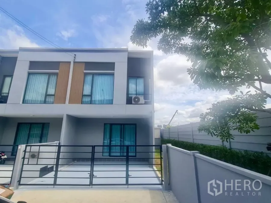 Townhouse for rent in Bang Phli, Samut Prakan - Modern two-storey corner townhouse with gated parking and blue glass windows.
