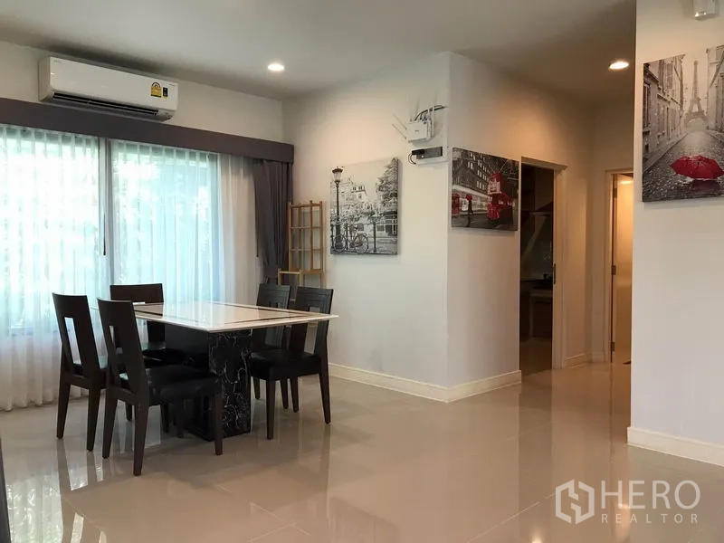 Detached House for rent in Bang Kapi, Bangkok - Dining area with four chairs by large windows and contemporary wall art.