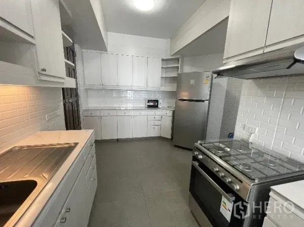 Condominium for rent in Khlong Toei, Bangkok - Bright enclosed kitchen with white cabinets, subway-tile walls, stainless refrigerator, and gas stove in a Bangkok condo.