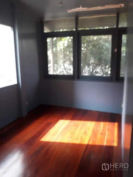 Detached House for rent in Watthana, Bangkok - Bedroom with large windows and polished wooden flooring.