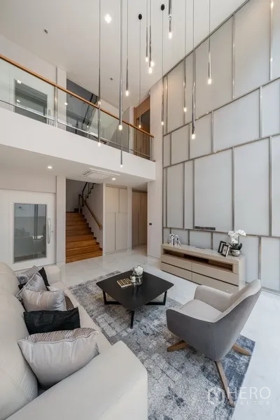 Detached House for rent or sale in Yan Nawa, Bangkok - Loft-style lounge with tall feature wall, pendant lights and mezzanine railing.